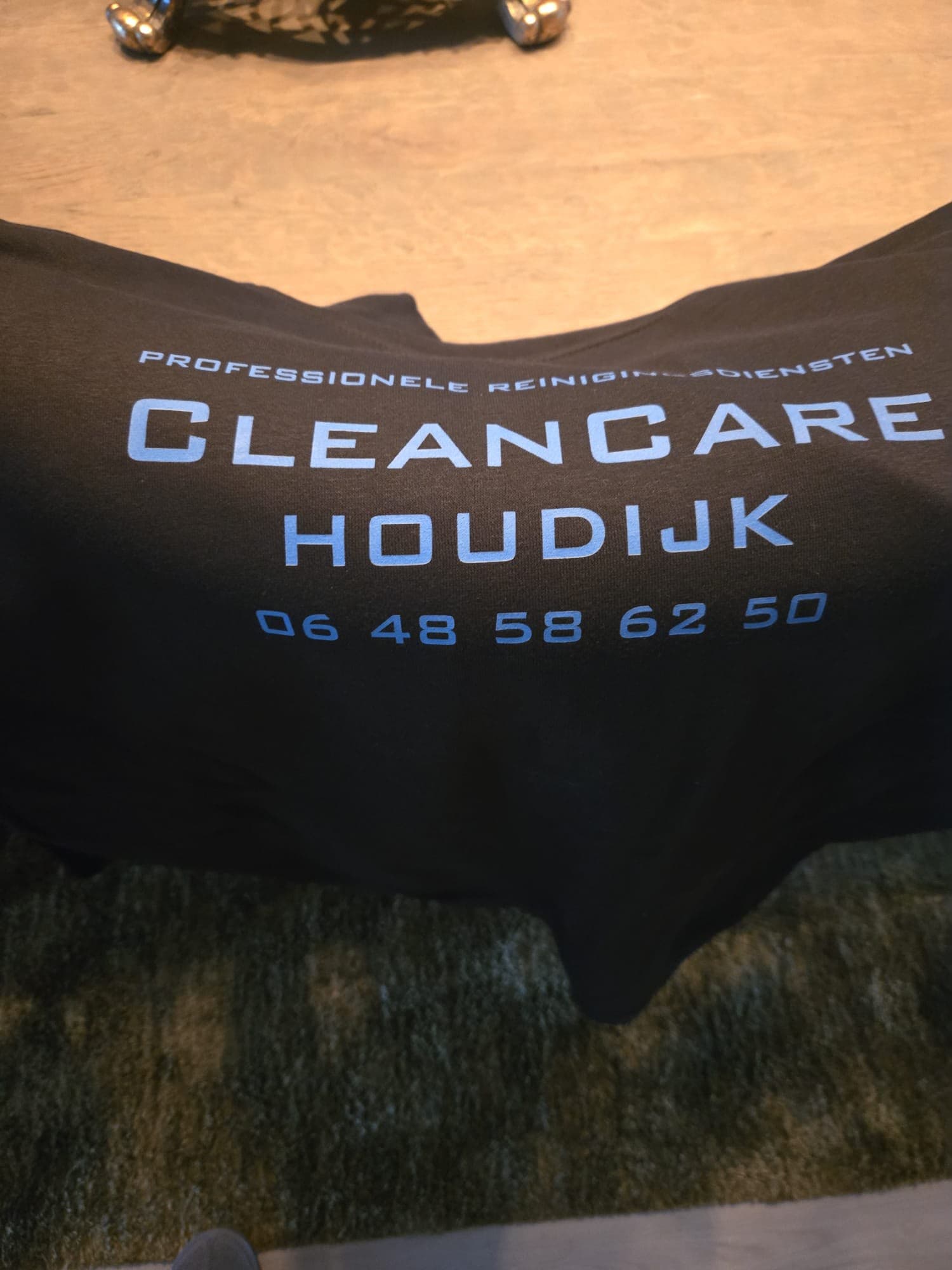 Achterkant van de Cleancare Houdijk hoodie met bedrijfsnaam en telefoonnummer